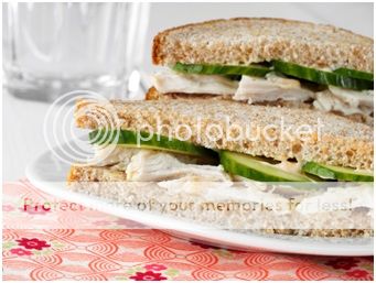 A sandwich cut in half on a plate, with Chicken and Cucumber
